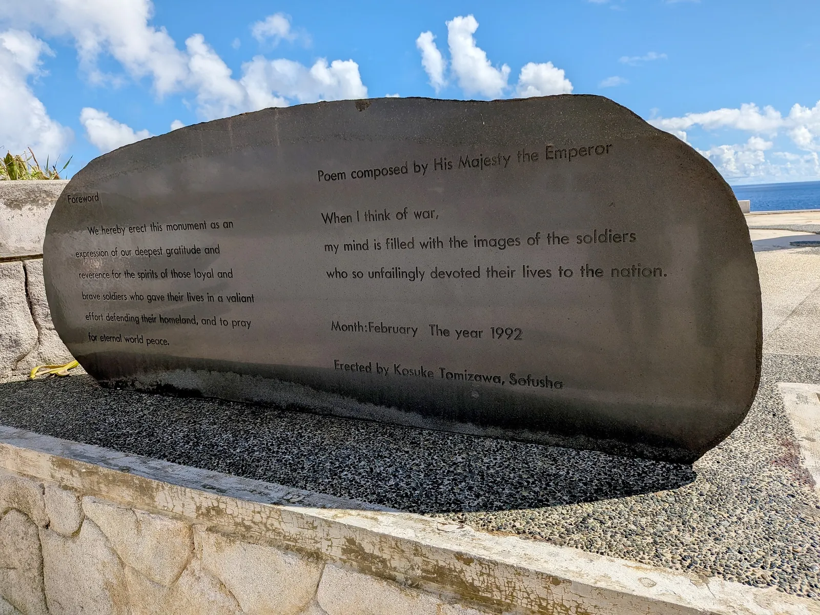 A polished stone monument at Banzai Cliff carrying an English translation of a poem composed by the Emperor, dated February 1992