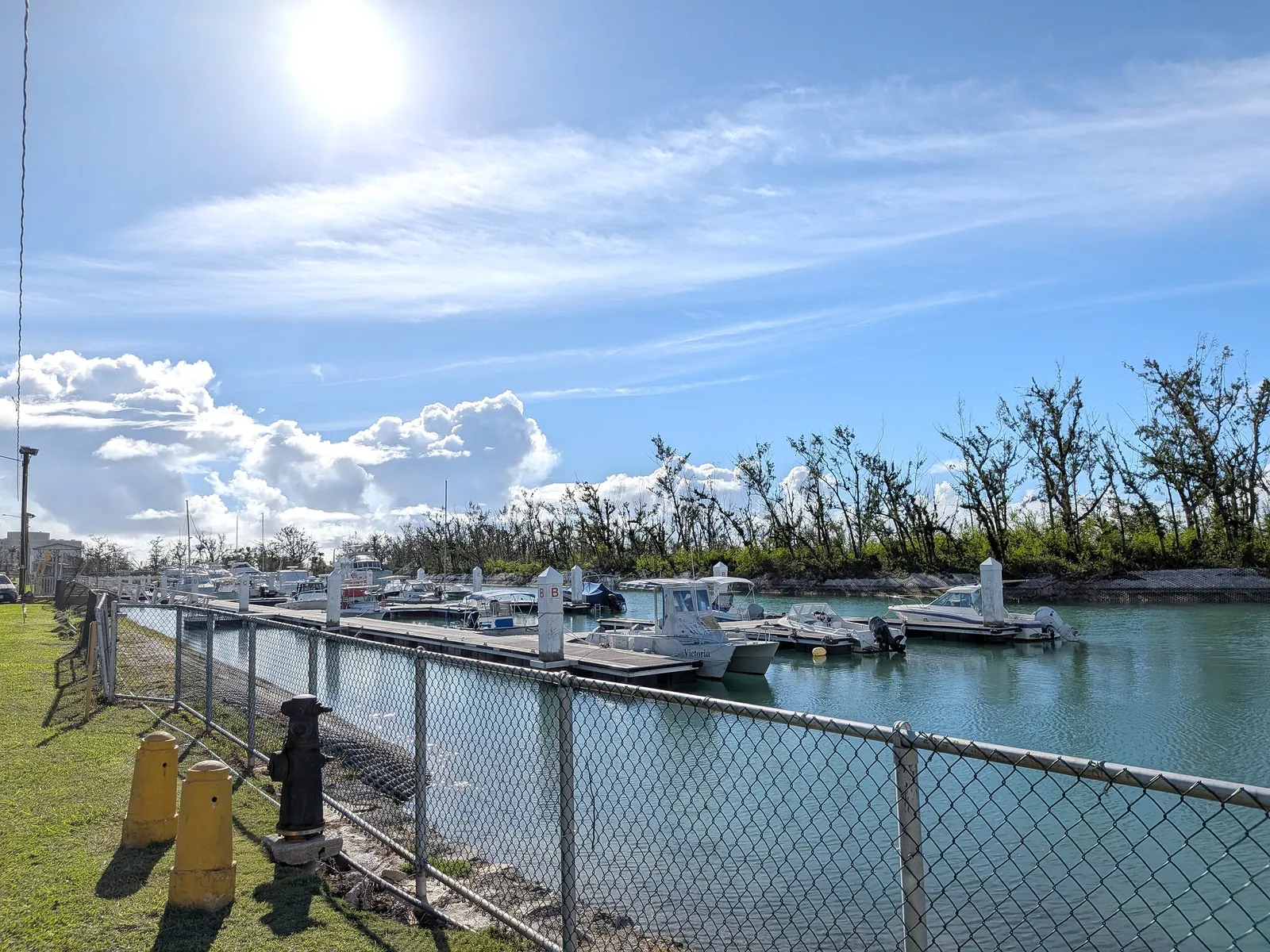 Boats docked at the working inner marina at Smiling Cove, Saipan, seen across a chain-link fence