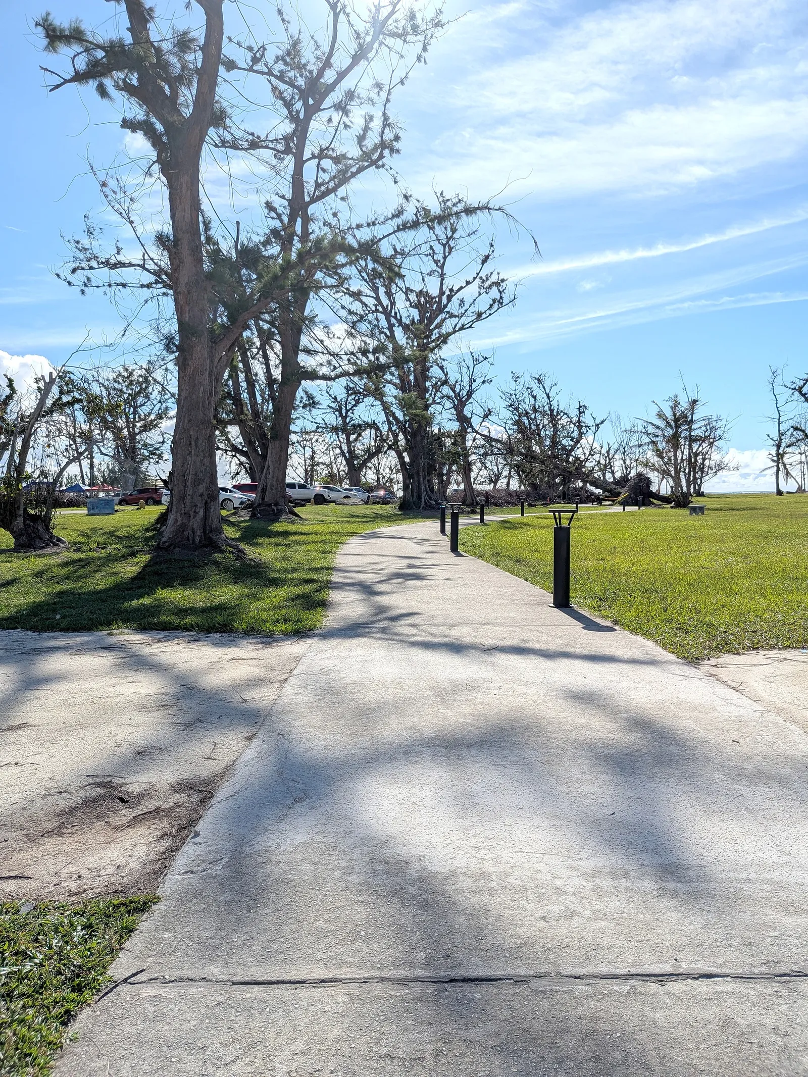 Micro Beach's walking path curving past the parking area, with tents set up by locals visible in the distance