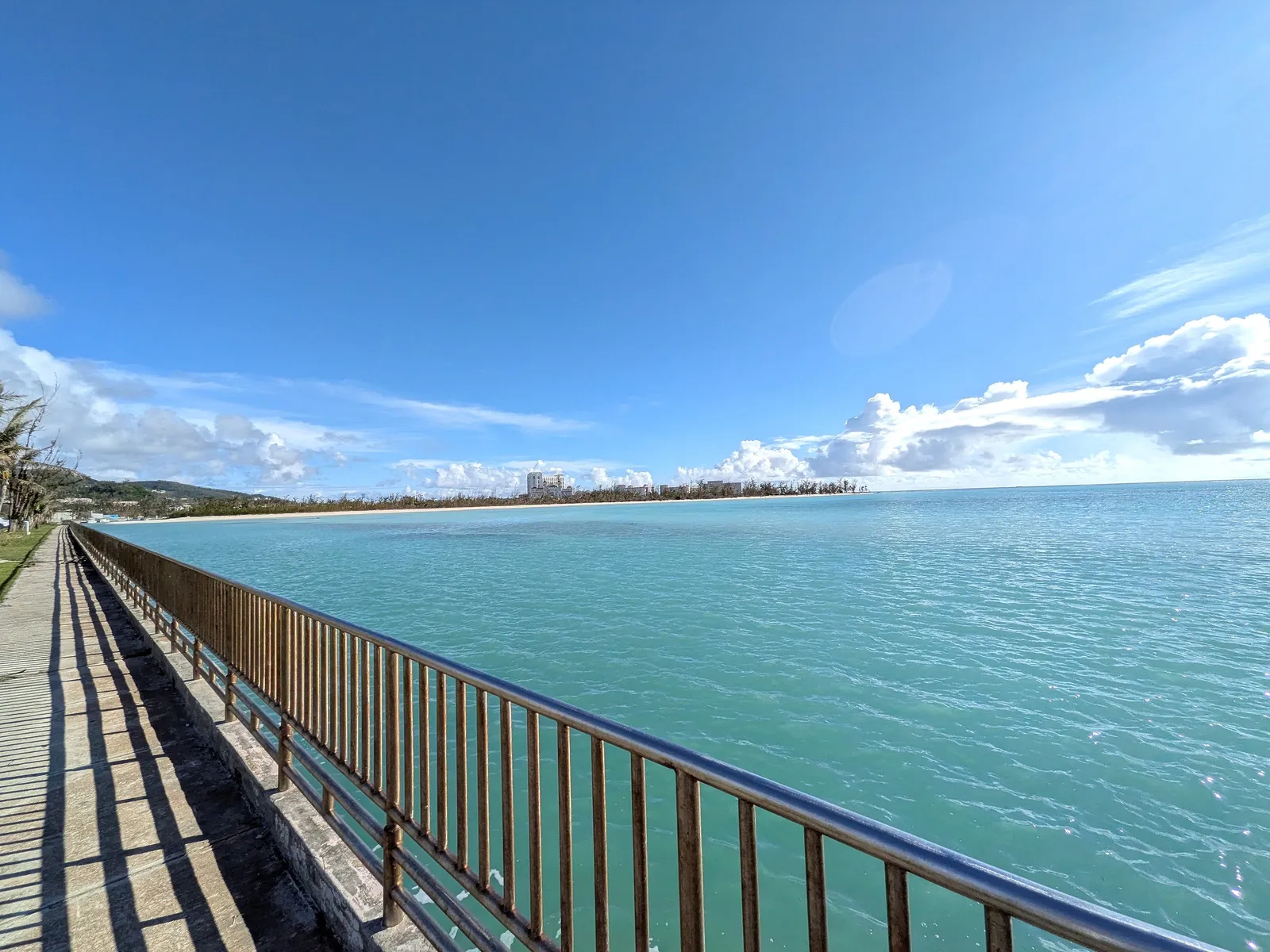 The seawall path at Smiling Cove looking back toward the Garapan hotel strip across the lagoon