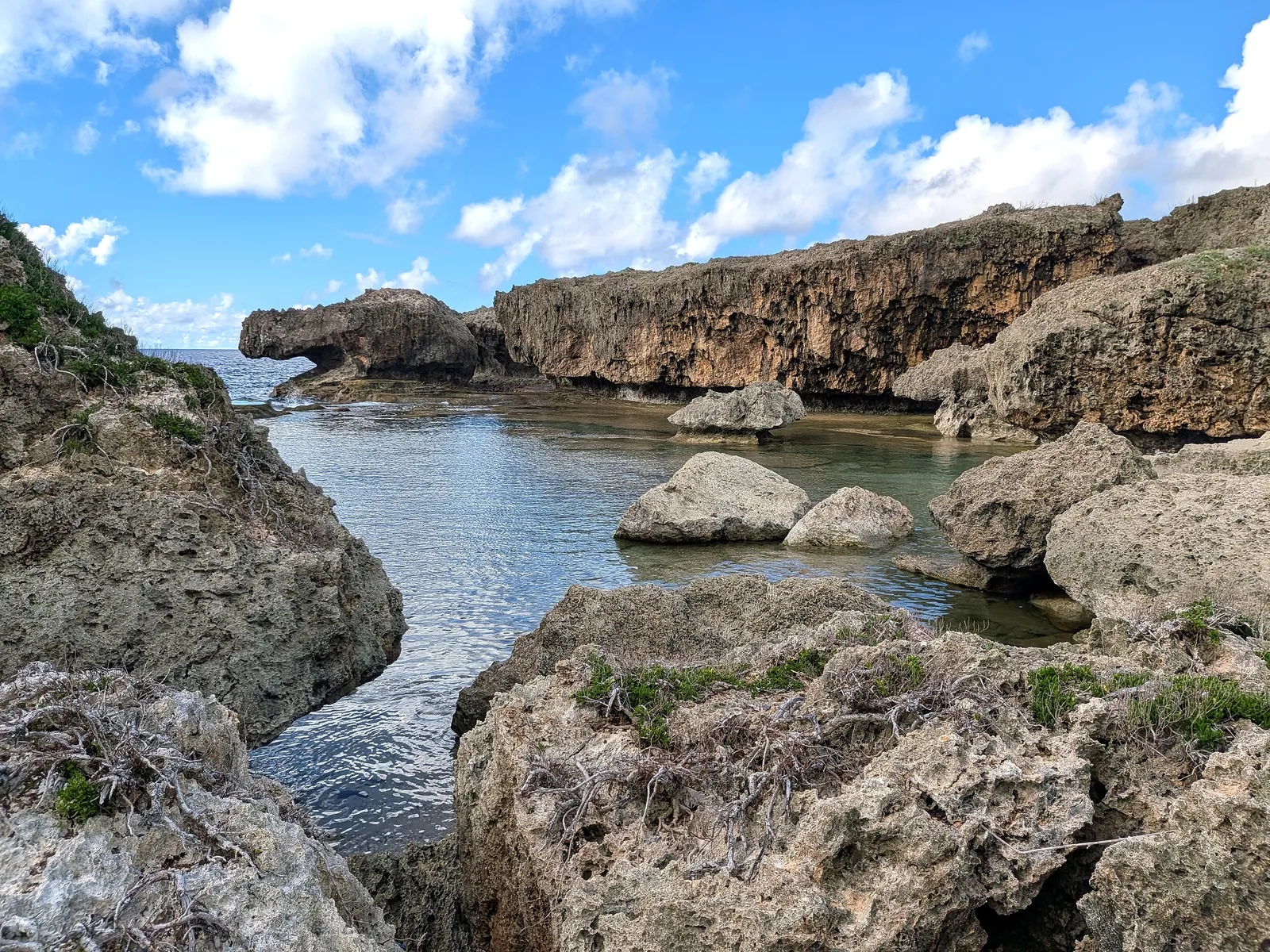 A shallow tidal channel running between limestone outcrops at Unai Fanhang toward the open sea
